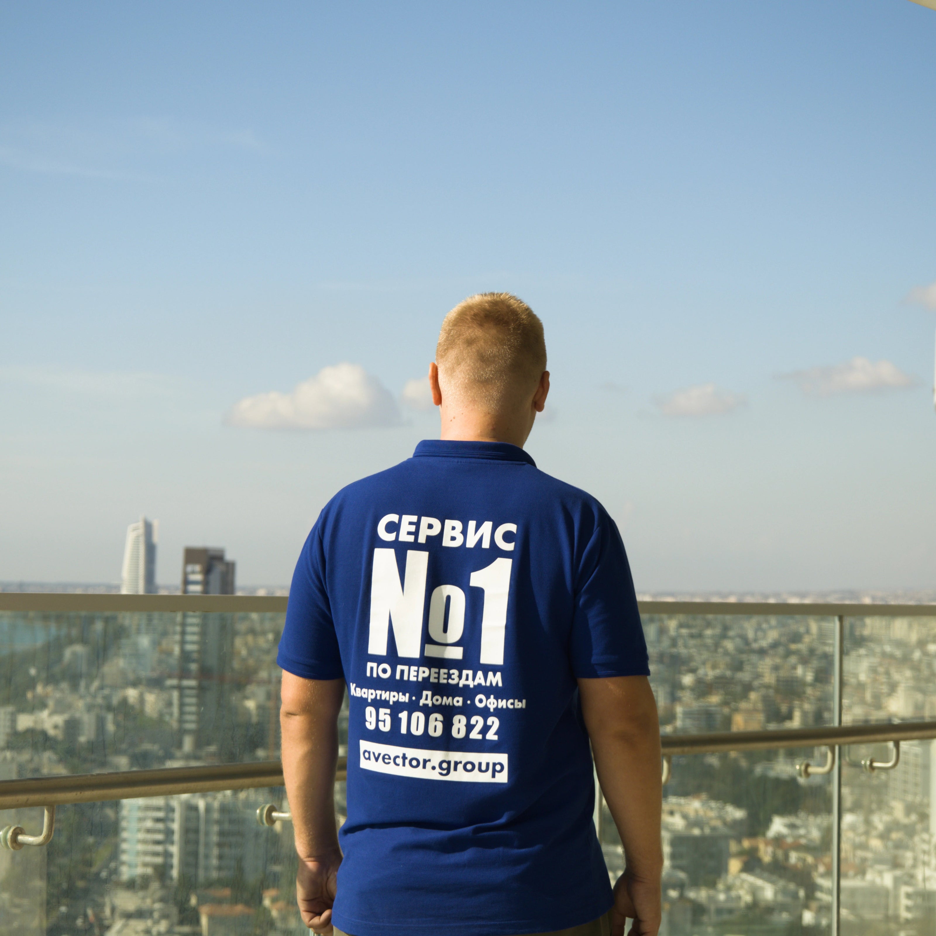 Person wearing a blue Avector t-shirt with text standing on a balcony overlooking Limasol Cyprus.
