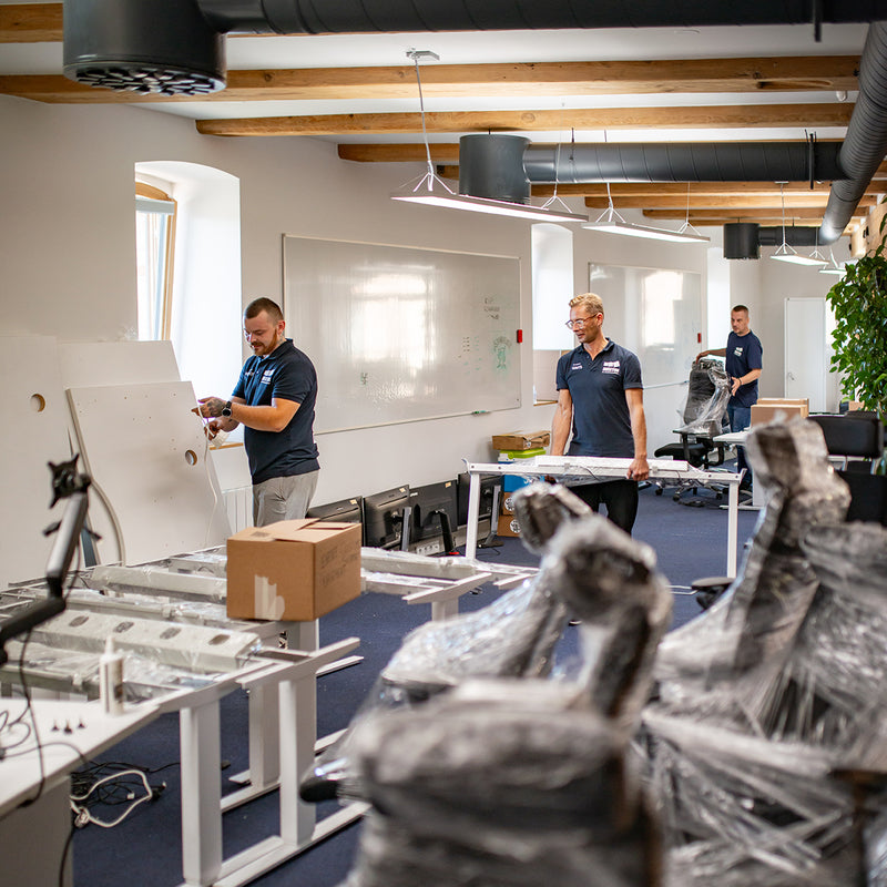 Two men in a modern office setting with office furniture and equipment.